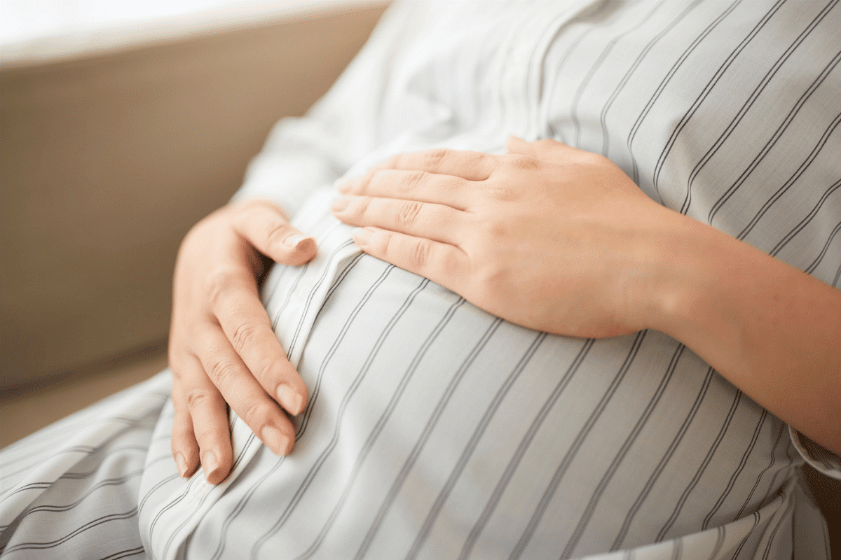 Pregnant woman gently holding her belly at home, maternity care, pregnancy health, prenatal wellbeing, expecting mother lifestyle concept. Washington pregnancy accommodations law takes effect in 2027
