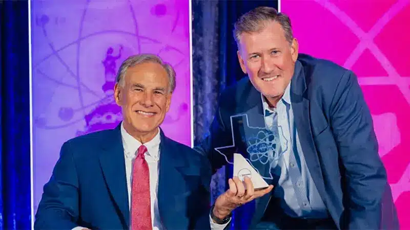 Governor Greg Abbott poses with an award alongside another man at an event.