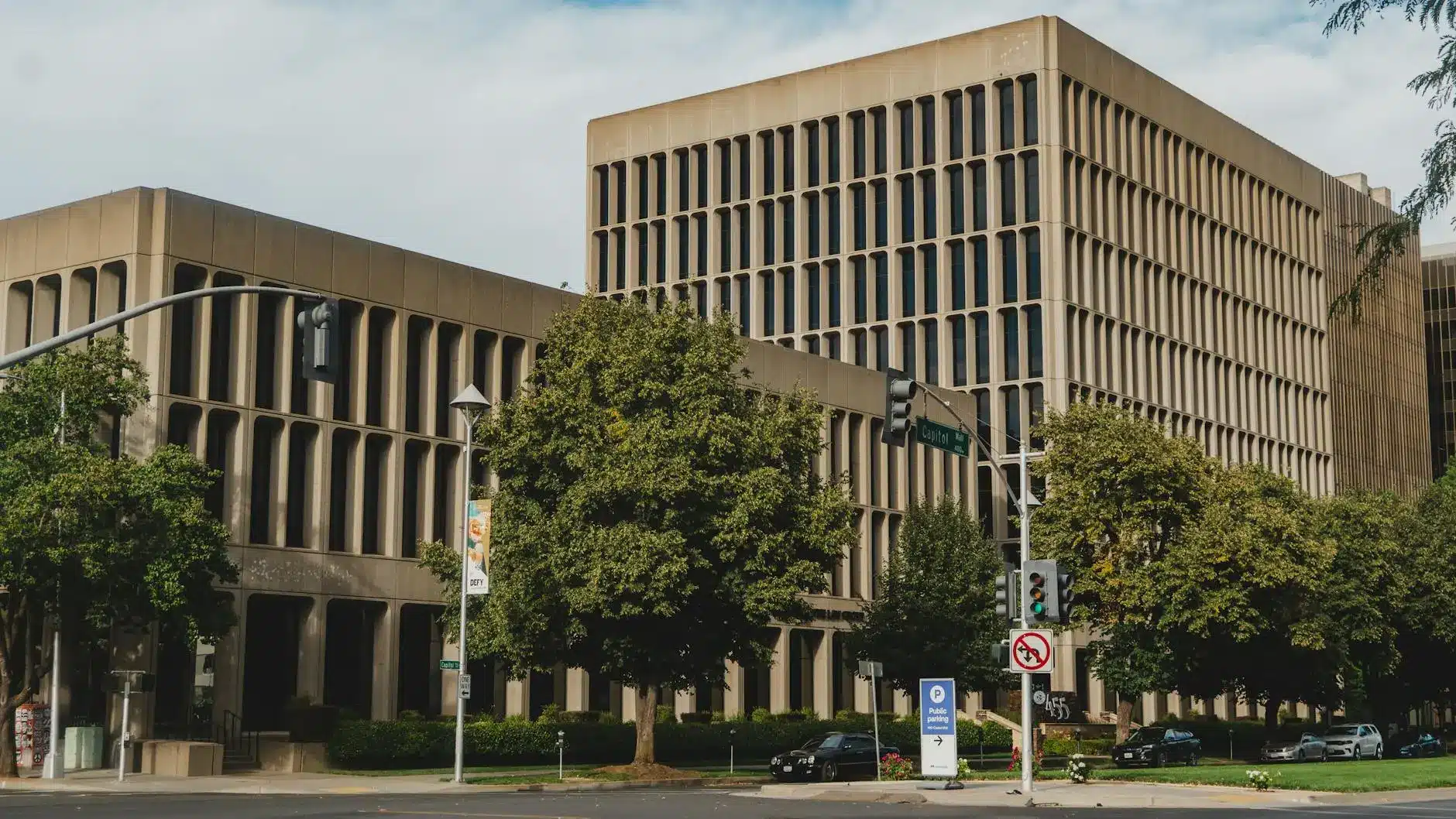 Office building with modern architecture, trees, and traffic signals.