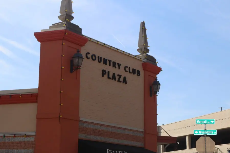 Sign of Country Club Plaza storefront in Kansas City with street signs visible.