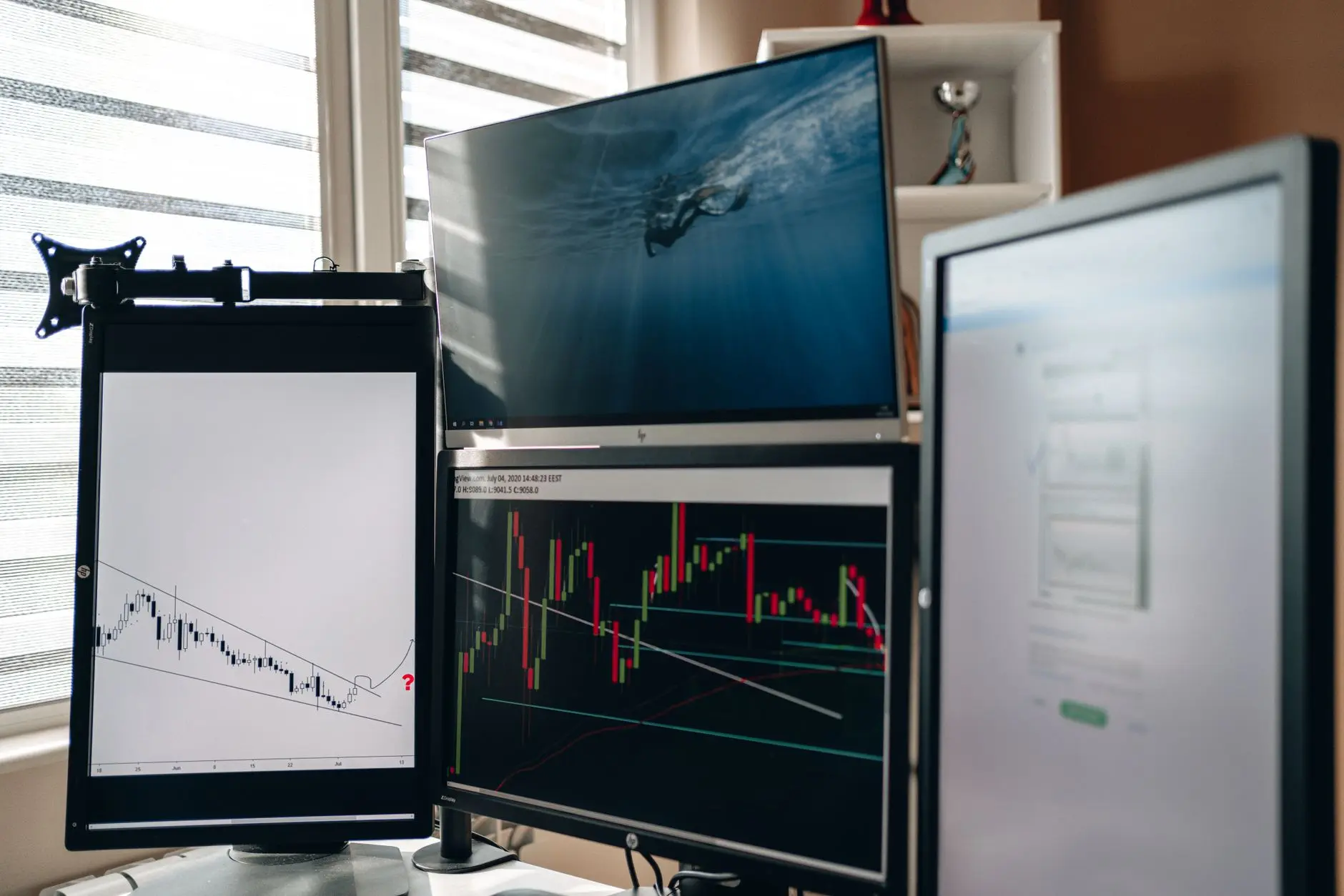 Multiple computer monitors displaying analytics and financial charts.