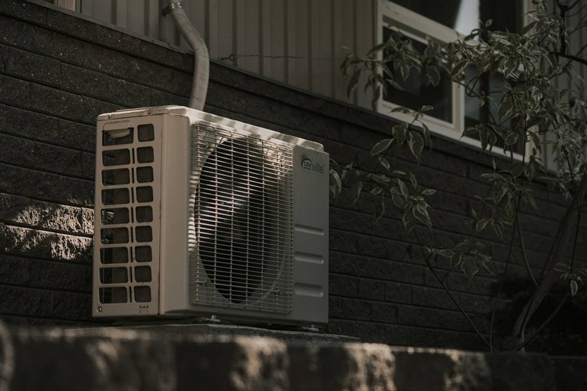 A white air conditioner sitting on the side of a building.